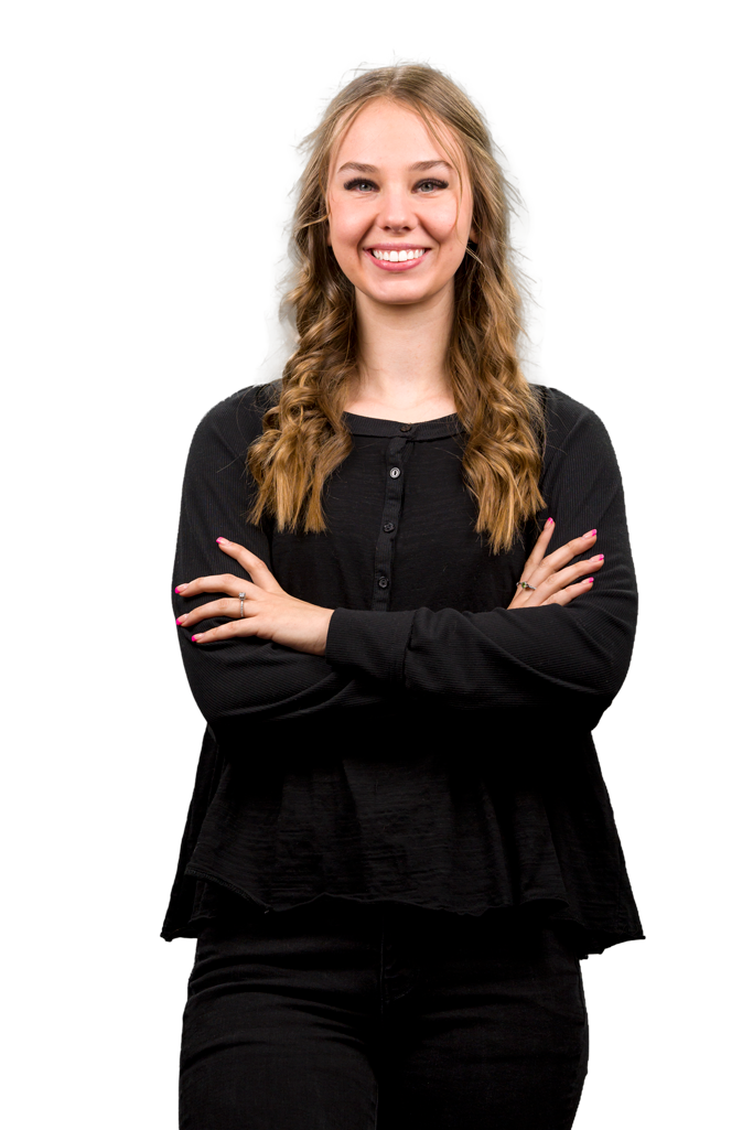 A woman in a black shirt is standing with her arms crossed and smiling.