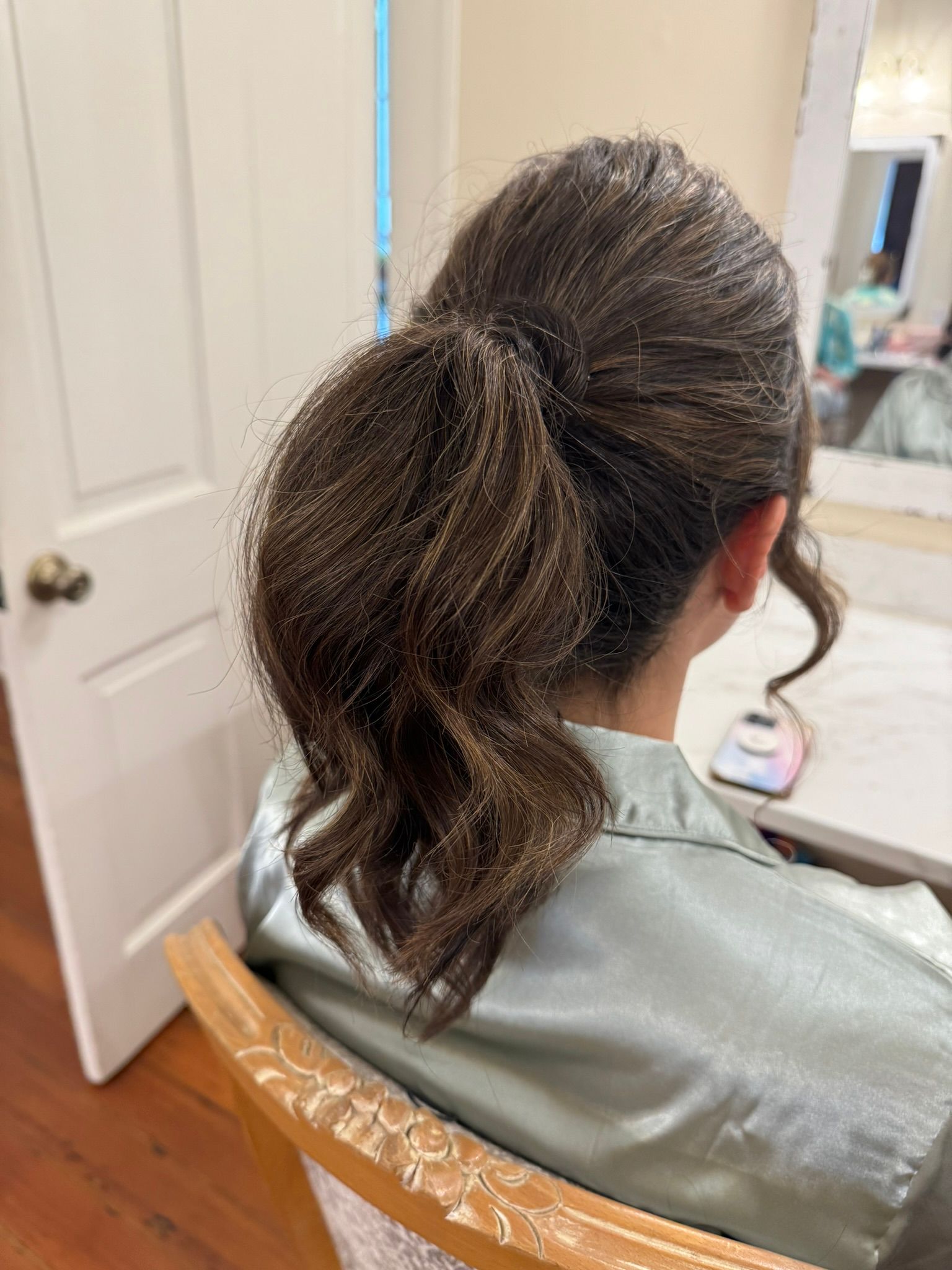 A woman is sitting in a chair with her hair in a ponytail