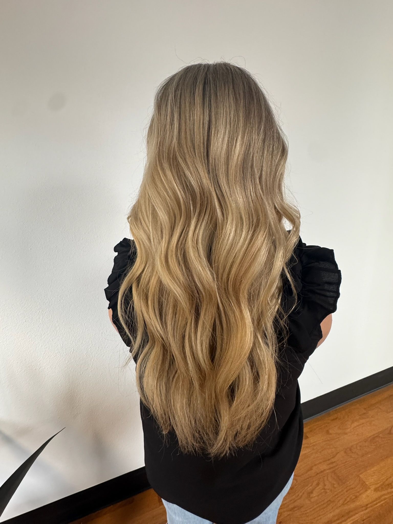 A woman with long blonde hair is wearing a black shirt and jeans