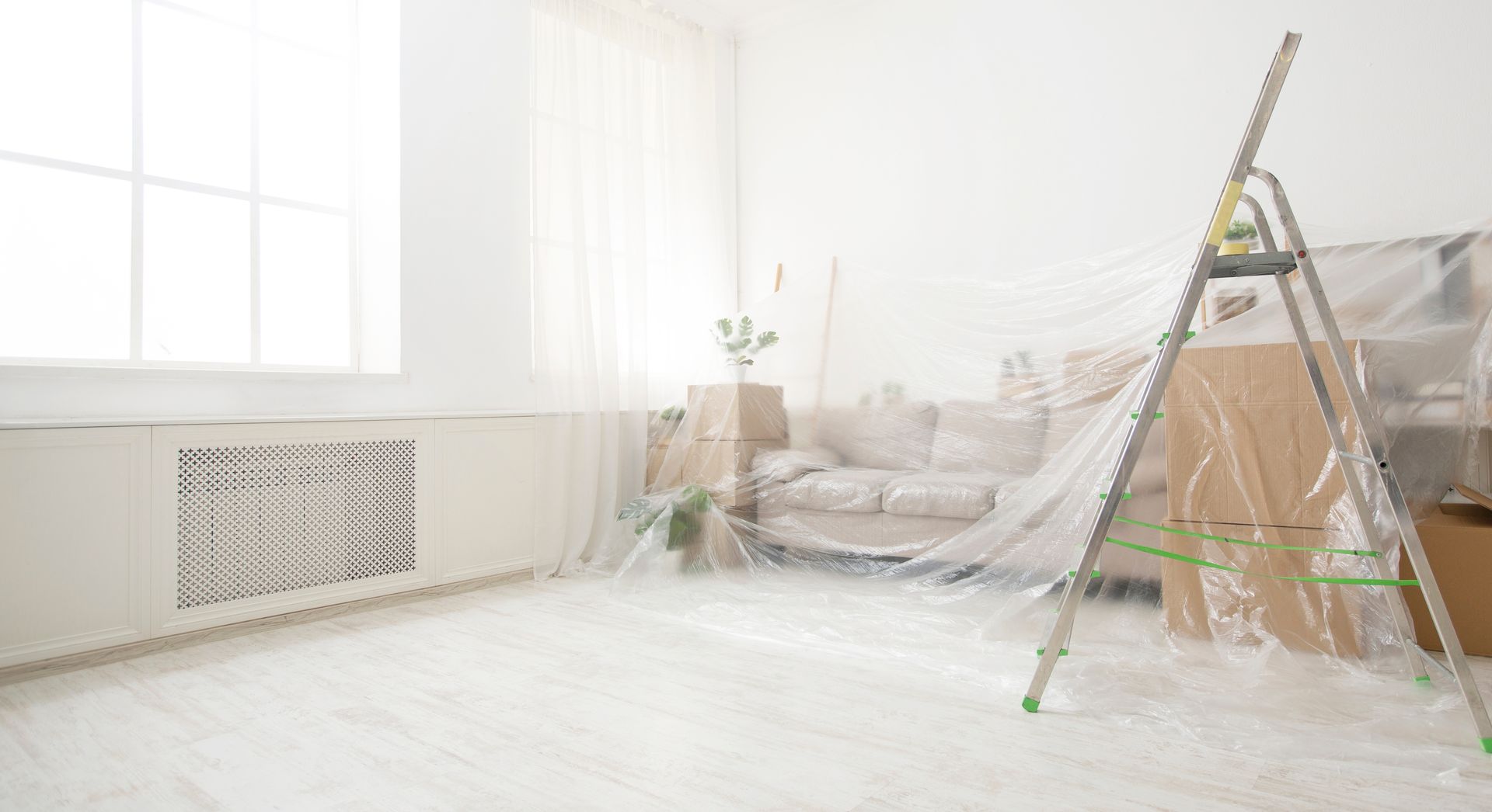 Sofa and boxes covered by dust sheets for renovation project