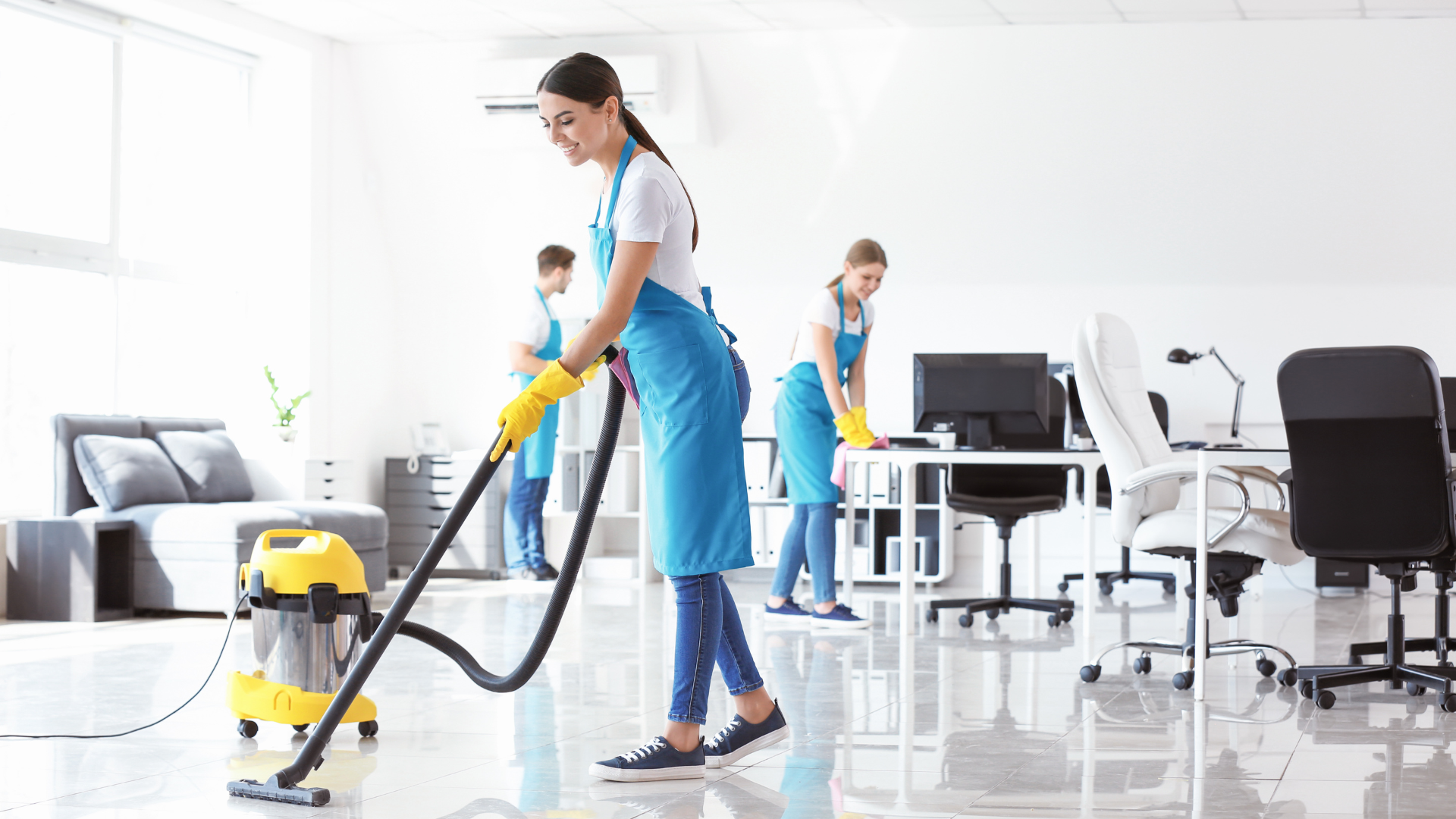 A woman is using a vacuum cleaner to clean an office.