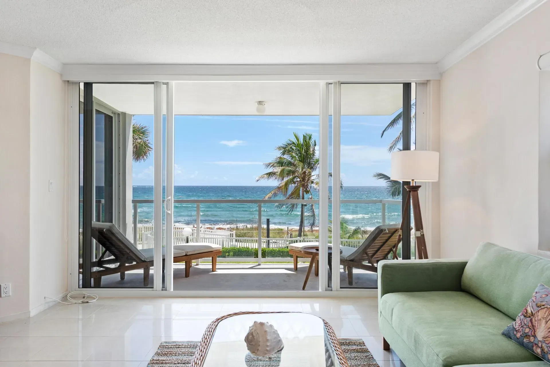 A living room with a green couch and a view of the ocean