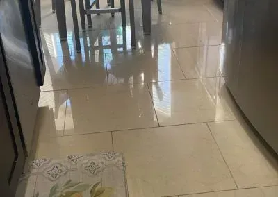 A kitchen floor with a rug on it and a table and chairs in the background.