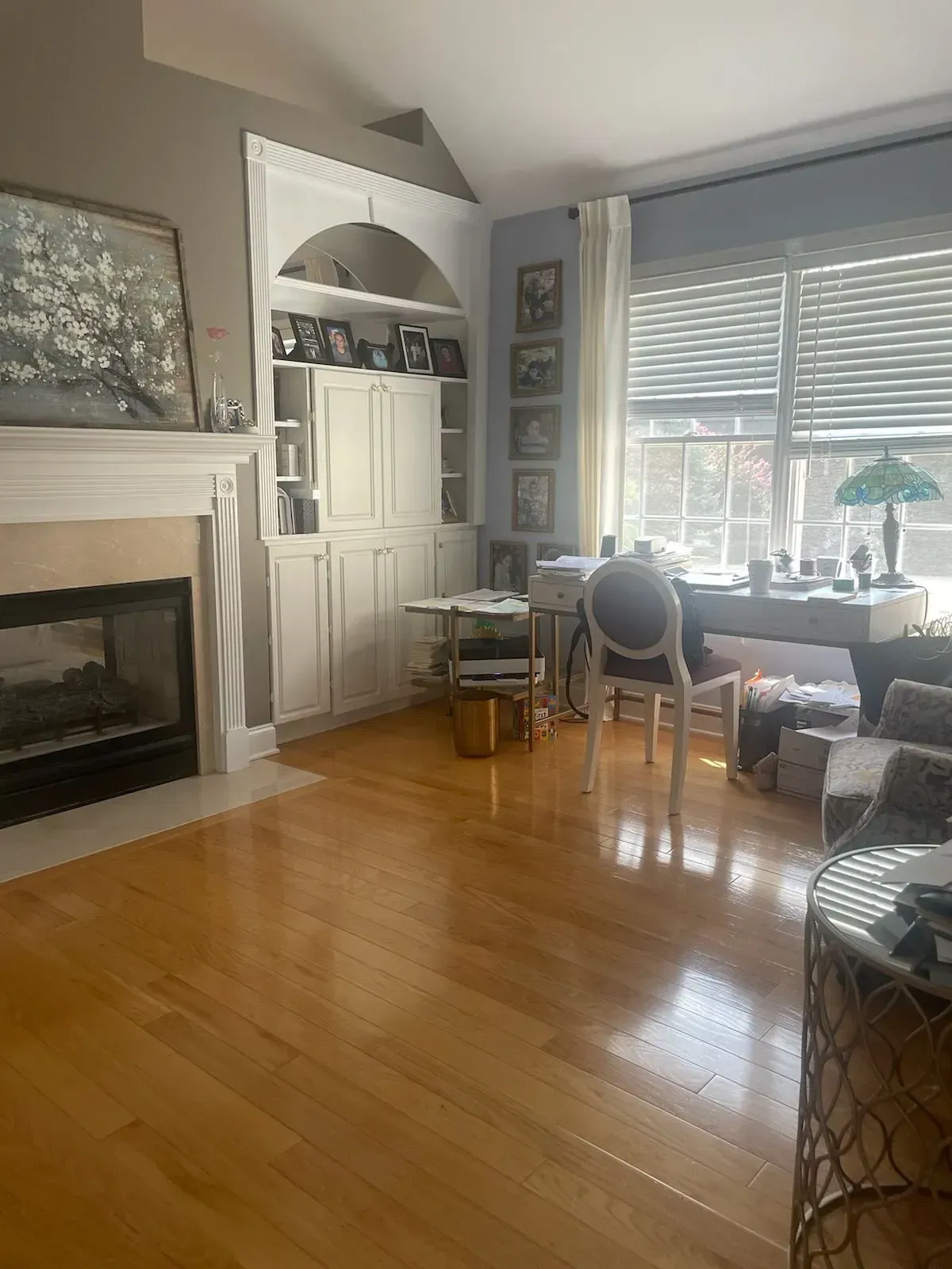 A living room with hardwood floors , a fireplace , a desk and chairs.