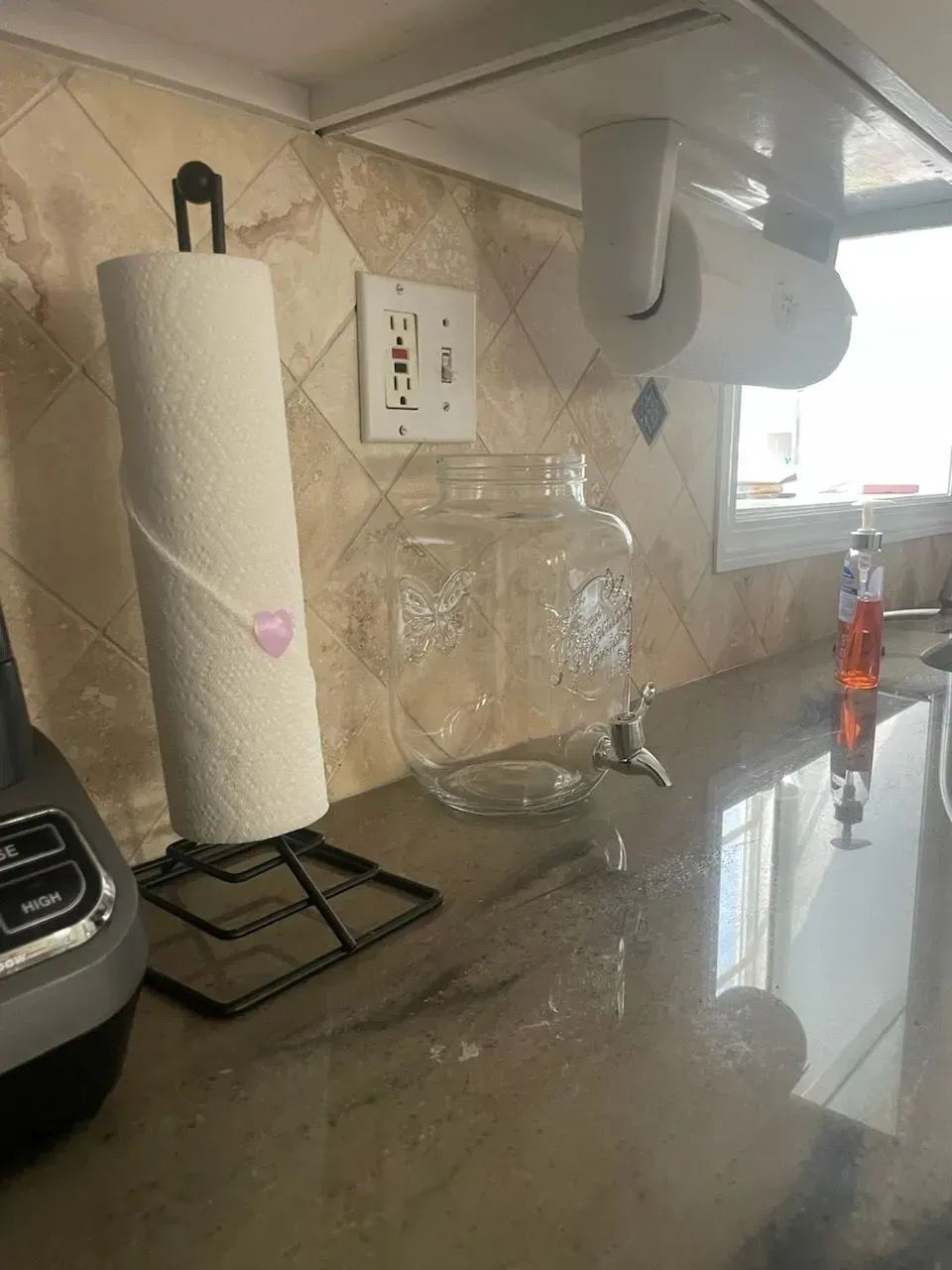 A kitchen counter with a paper towel holder and a water dispenser.