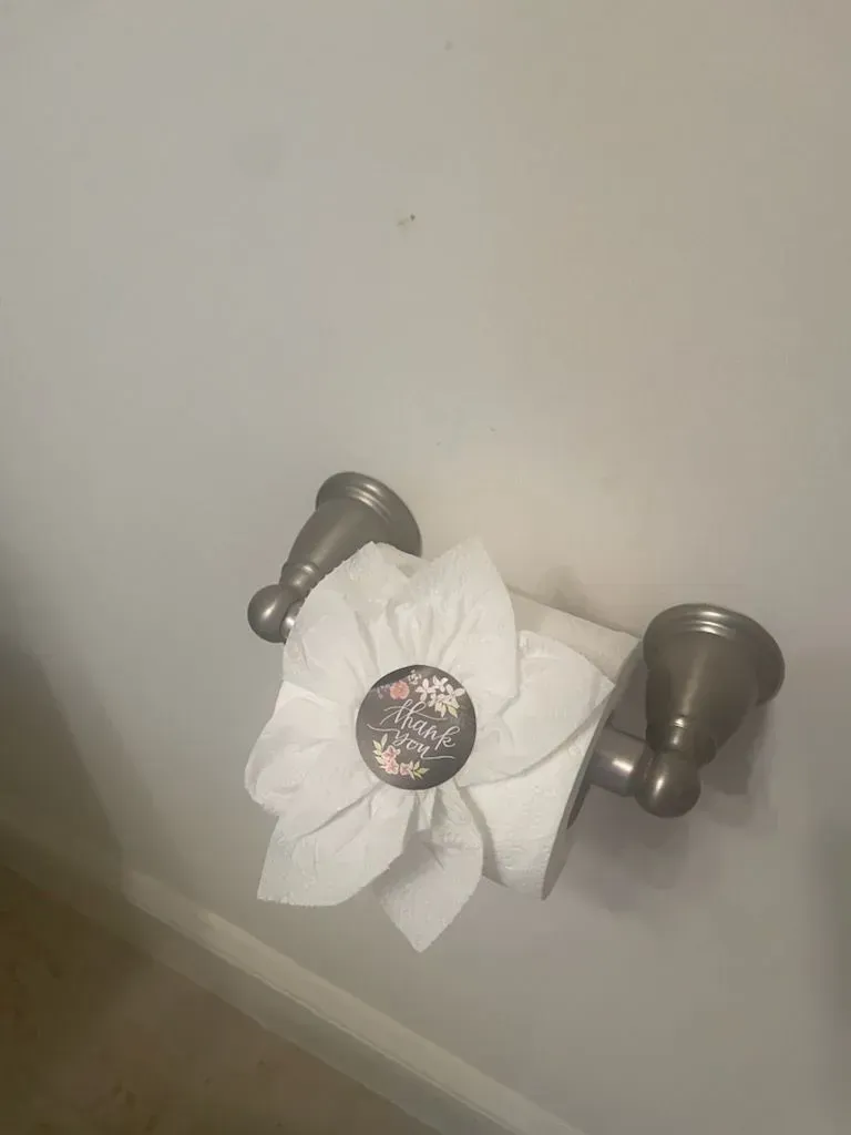 A toilet paper holder with a flower made out of toilet paper.
