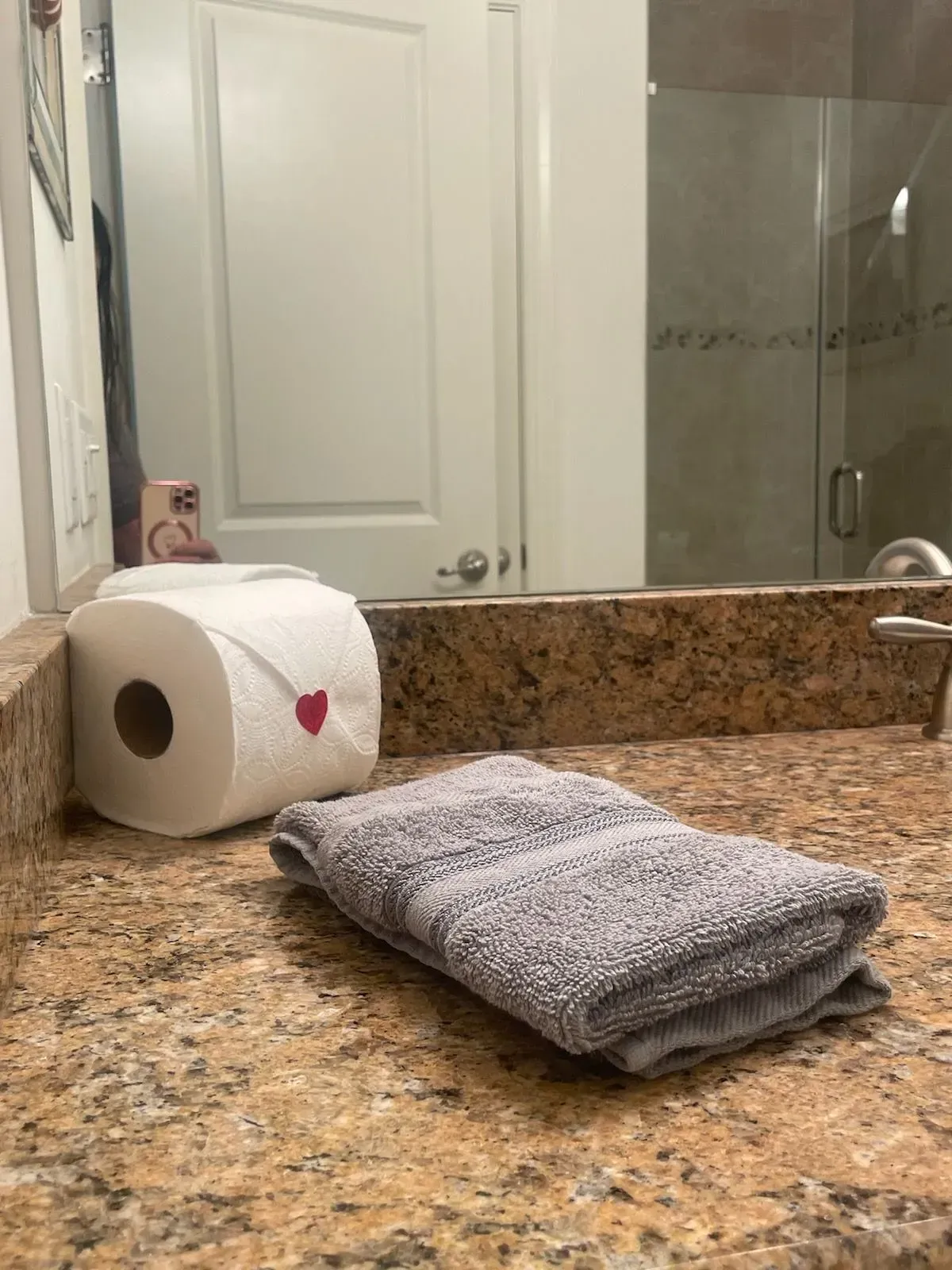 A roll of toilet paper and a towel are on a bathroom counter.