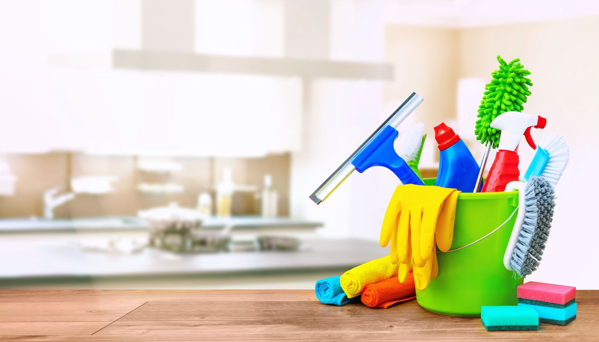 A green bucket filled with cleaning supplies on a wooden table.
