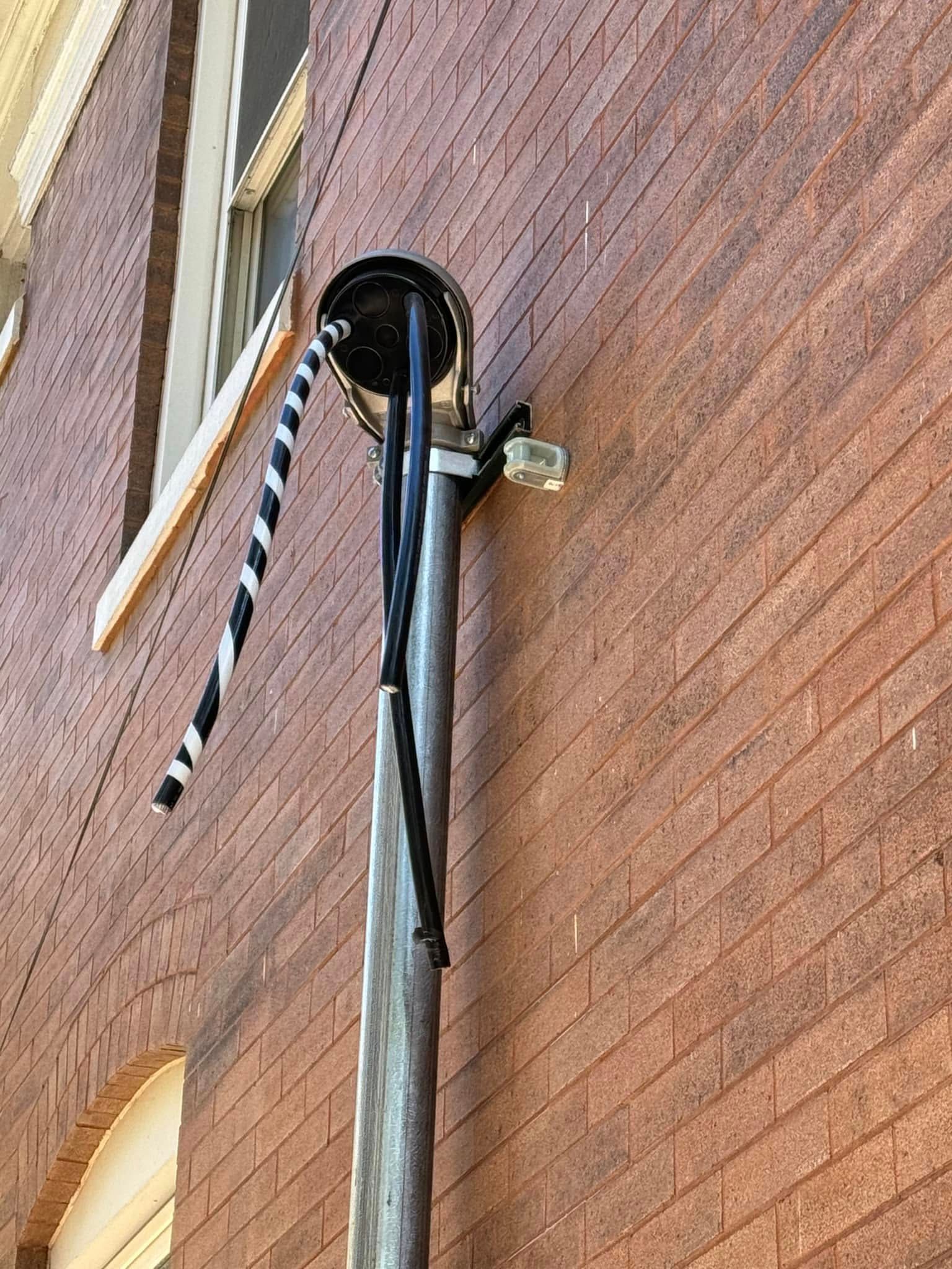 Black-and-white striped awning on a brick building with a vertical pole attached to the wall