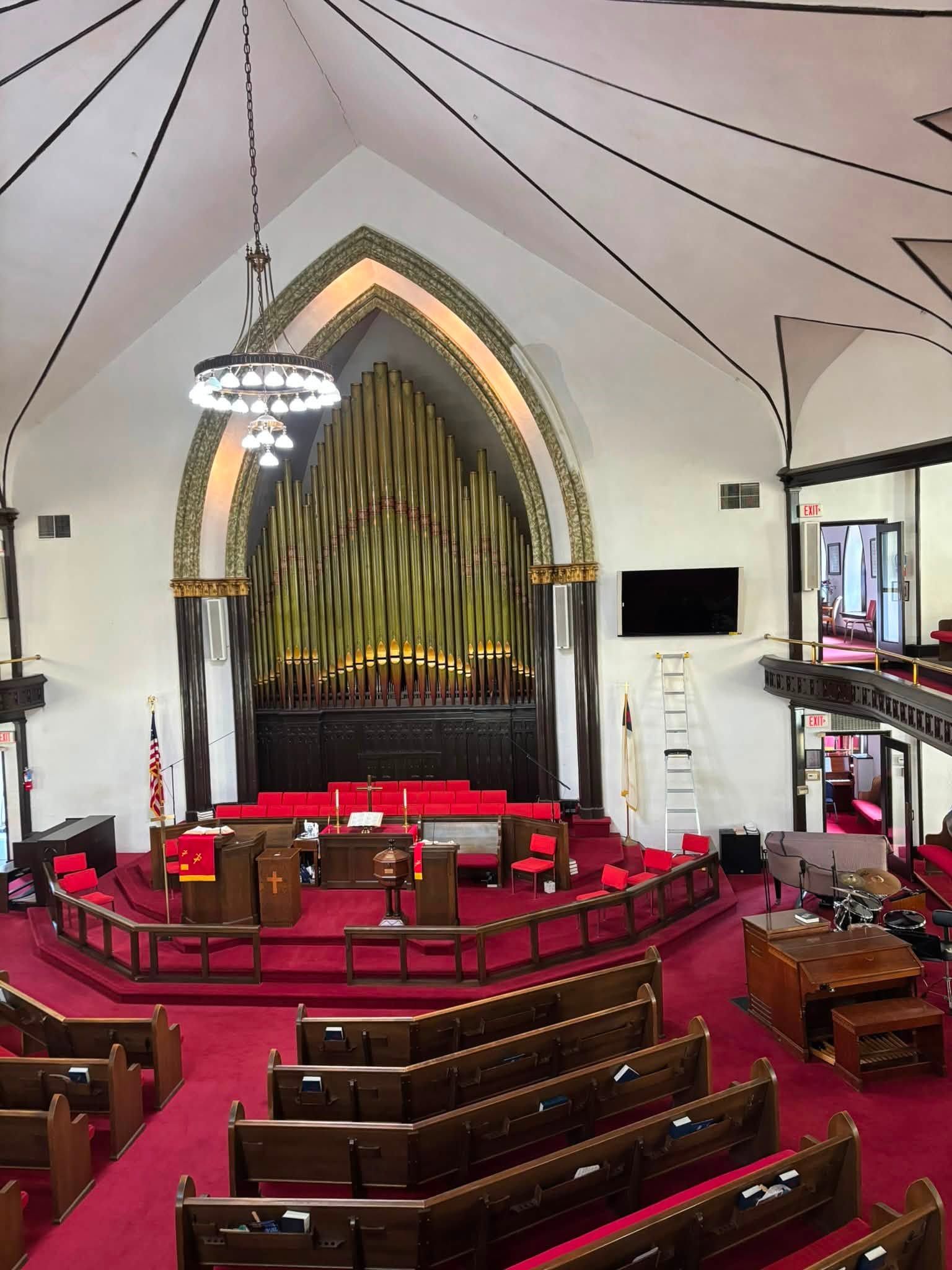Church sanctuary with red pews, arched organ pipes, and a white vaulted ceiling