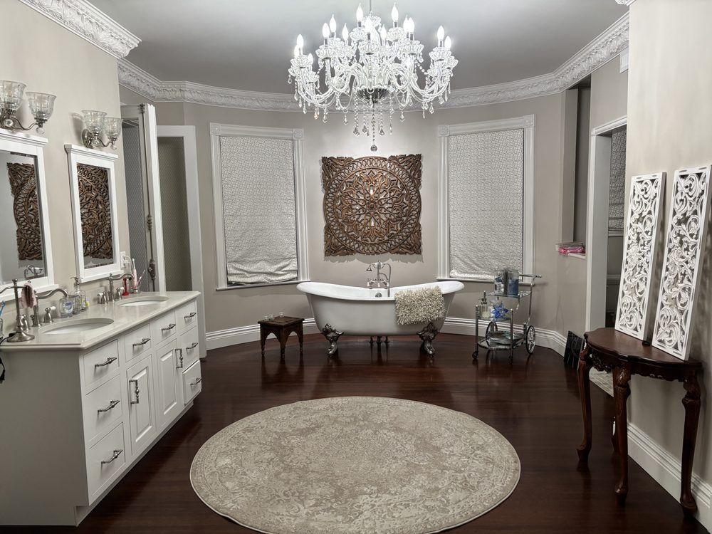 Elegant bathroom with white vanity, chandelier, freestanding tub, and dark wood floor