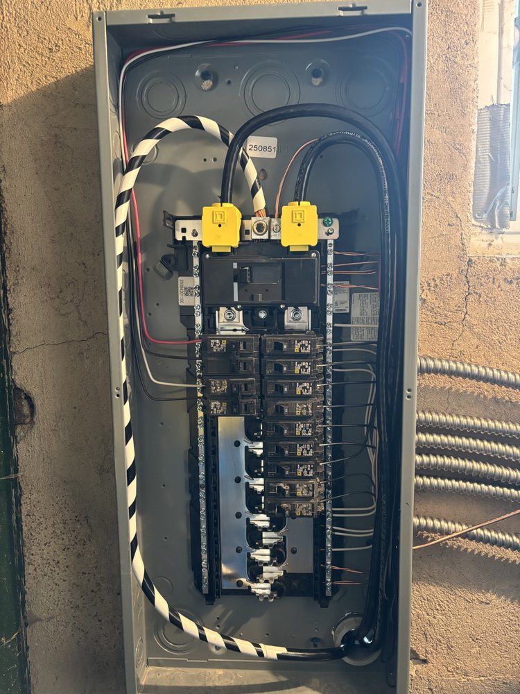 Open electrical breaker panel with wiring and breakers inside a wall-mounted box