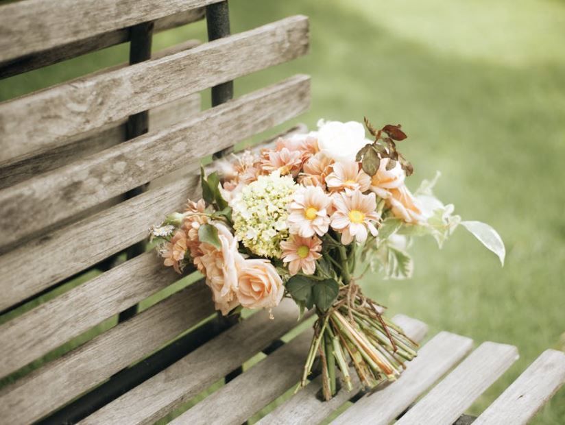 Pastel bouquet resting on a wooden bench, monument planning inspiration, funeral homes Phoenix, AZ