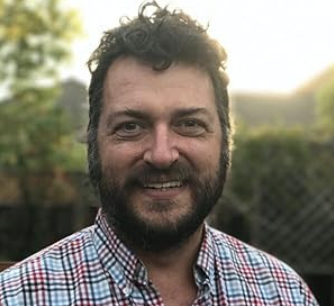 A man with a beard and a plaid shirt is smiling for the camera.