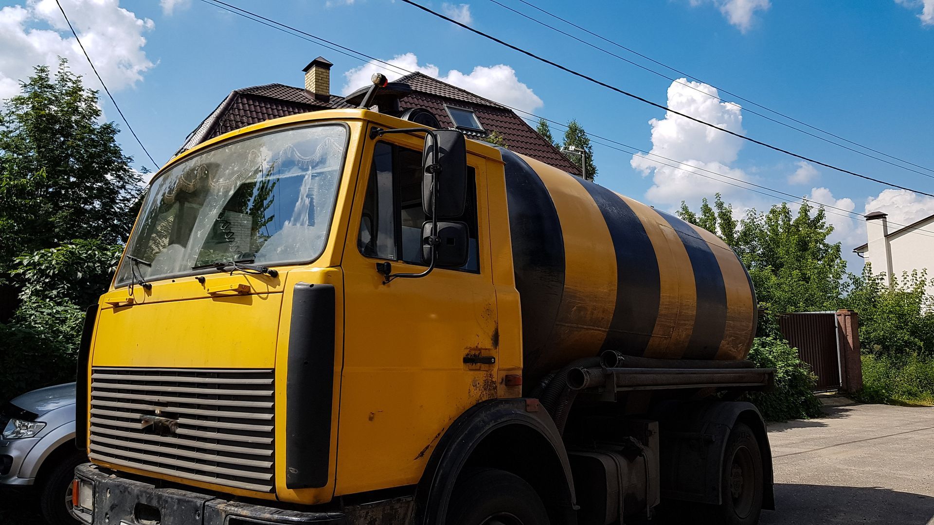 Yellow and black striped tanker truck parked outside under a blue sky.