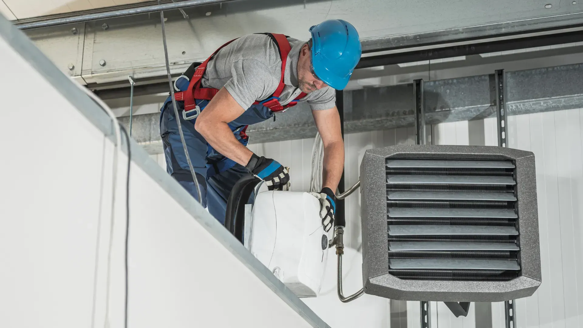 A man is installing a heater on the ceiling of a building.