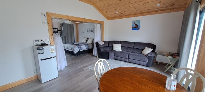 A living room with a couch , table , chairs and a refrigerator.