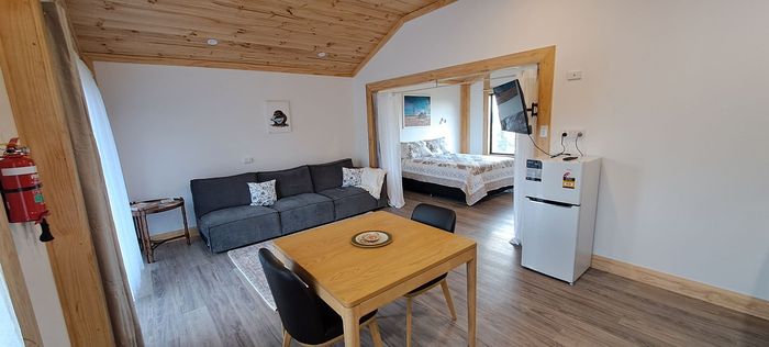 A living room with a couch , table , chairs and a refrigerator.