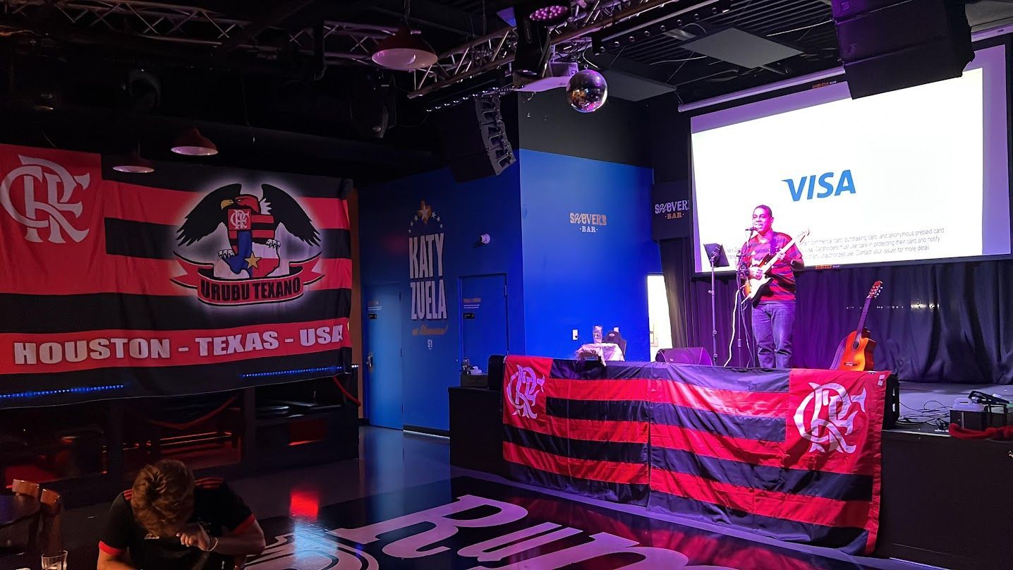 A man is playing a guitar on a stage in front of a large screen that says visa.