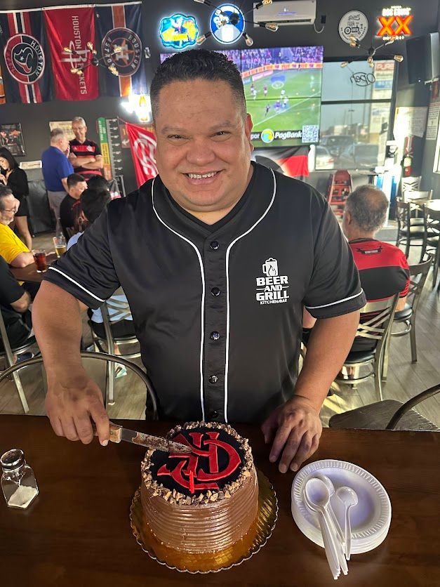 A man is cutting a birthday cake in a restaurant.
