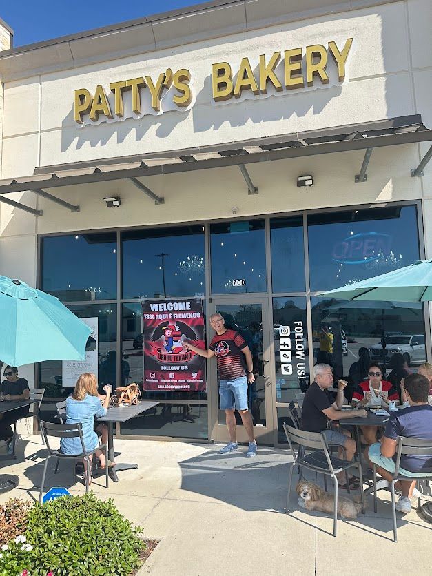 A group of people are sitting at tables outside of patty 's bakery.