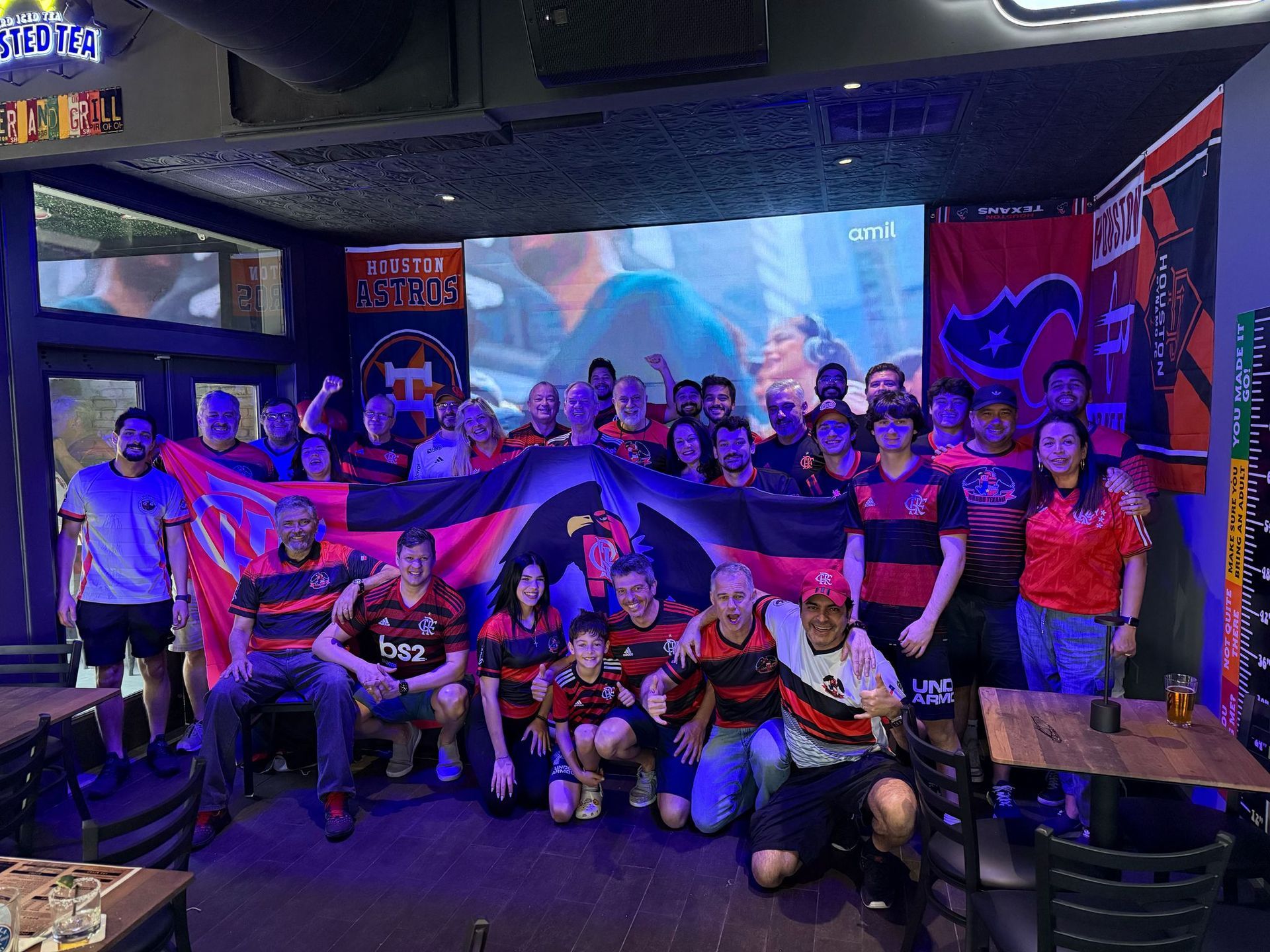 A group of people are posing for a picture in front of a large screen.
