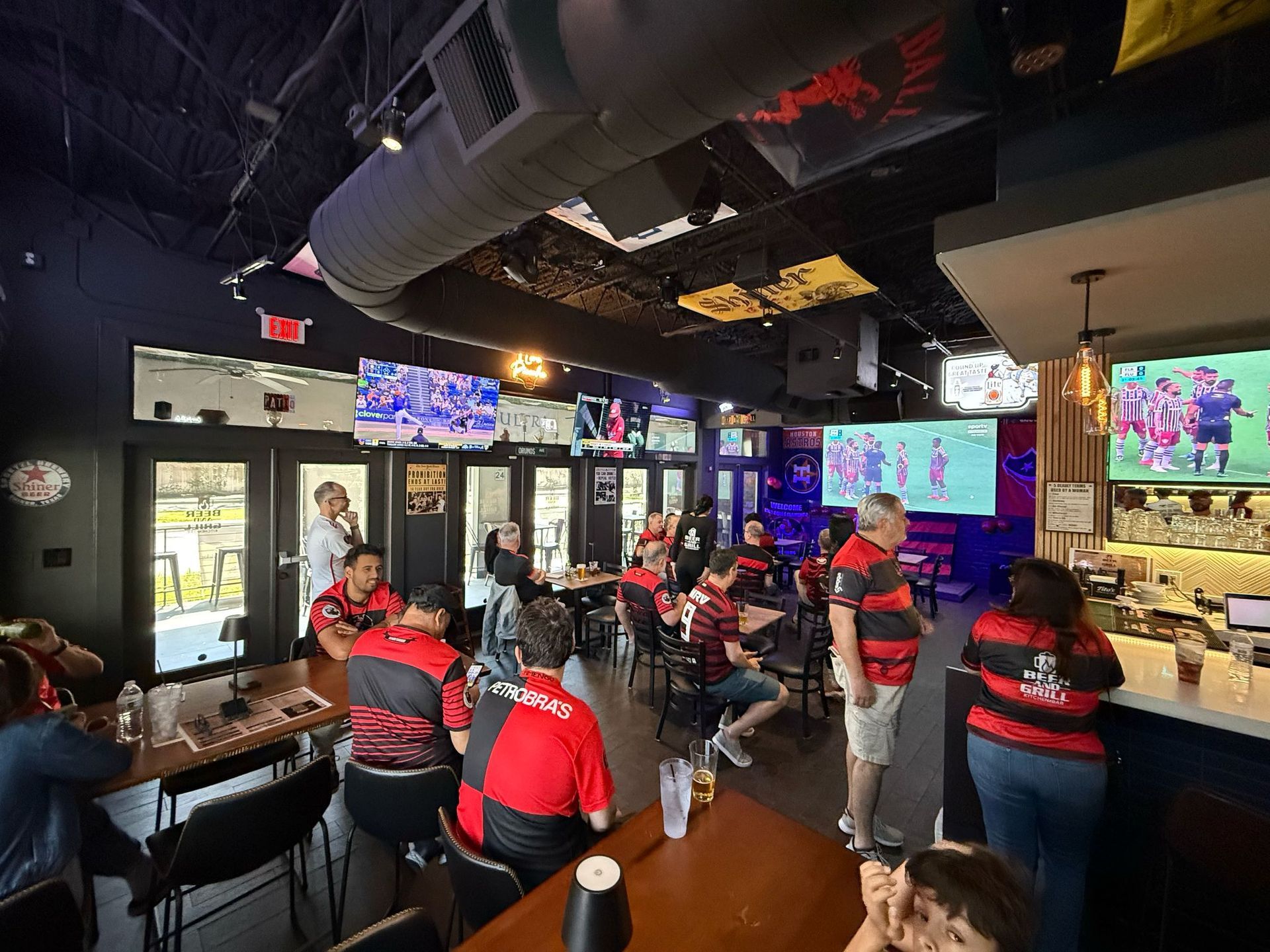 A group of people are sitting at tables in a restaurant watching a game.