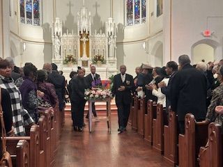 A group of people are standing in a church holding a coffin.