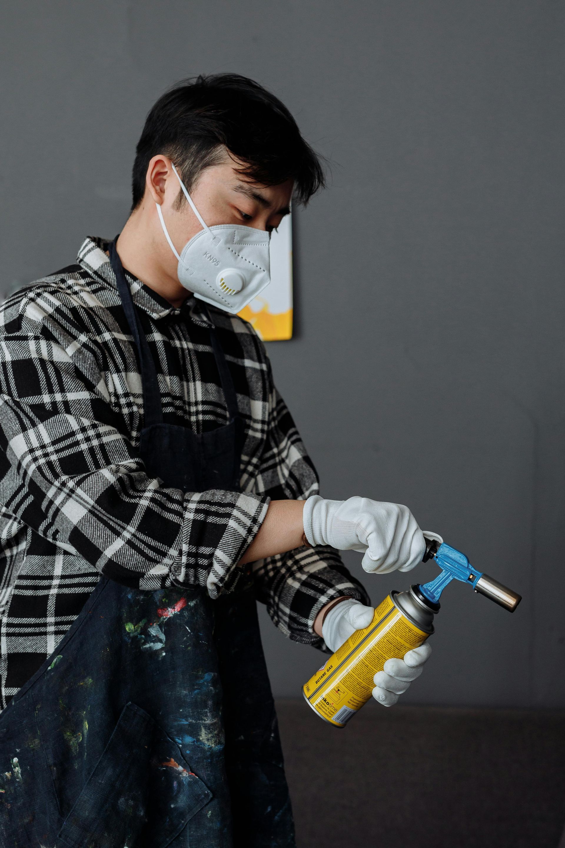 Een man met een masker en handschoenen houdt een spuitbus vast.