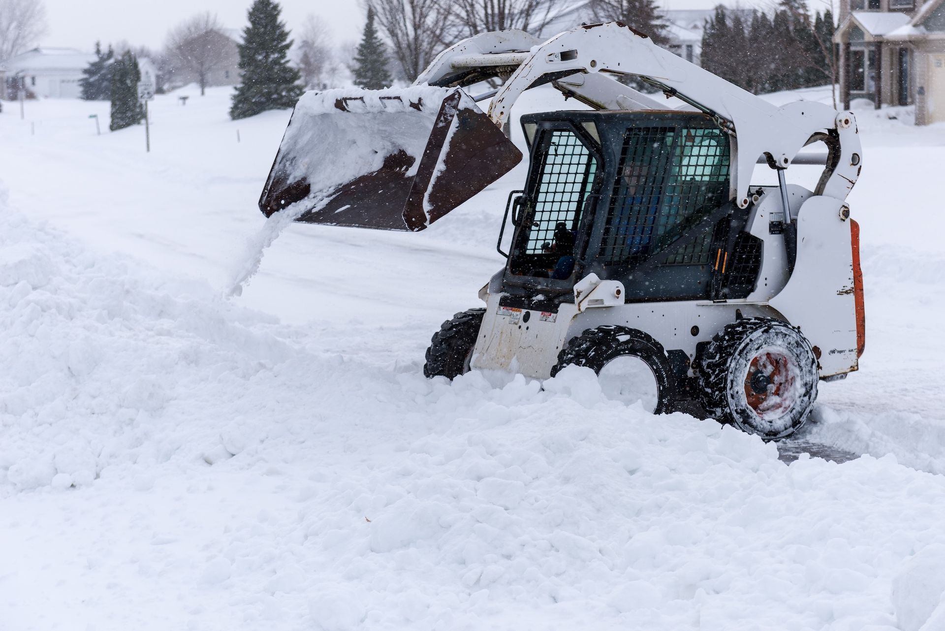 Skid-steer loader buried in deep snow on a snowy residential street