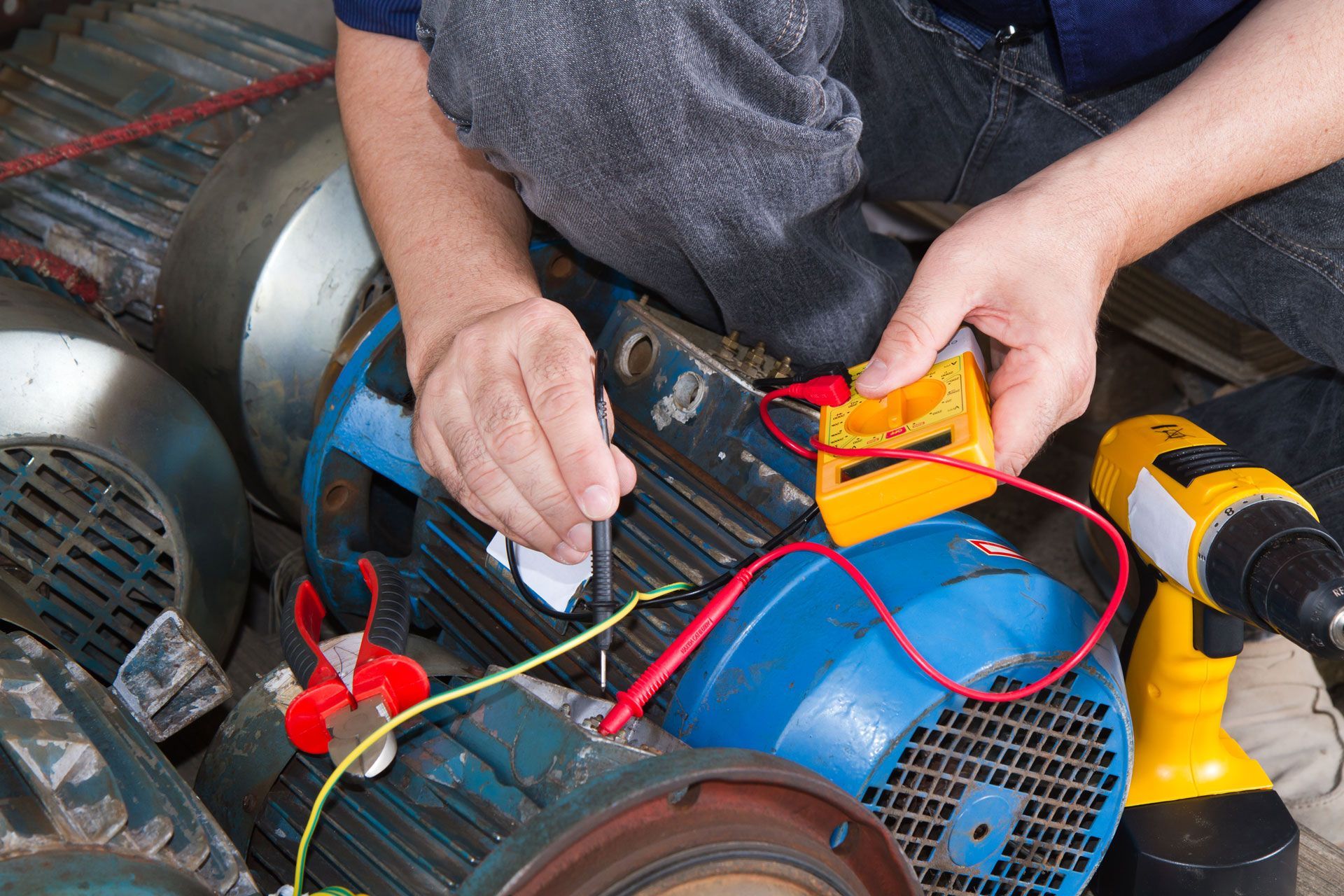 A man is working on a motor with a voltmeter.