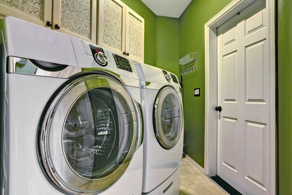 A Laundry Room With a Washer and Dryer and Green Walls — Hunter Kitchen King In Maitland, NSW