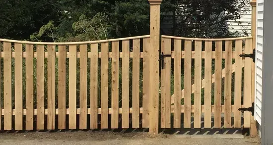 A close up of a wooden fence with trees in the background.