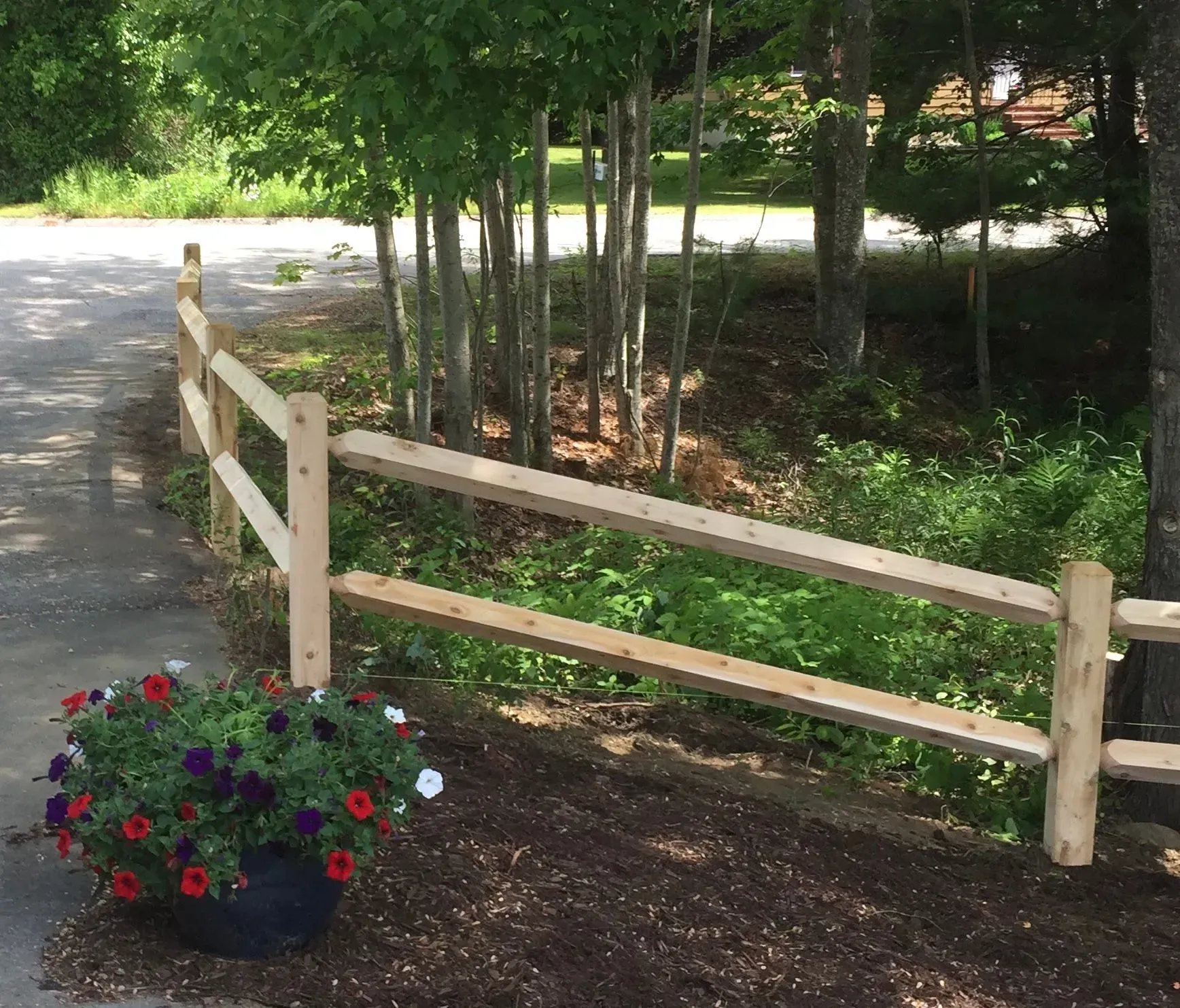 A wooden fence with flowers in a pot next to it
