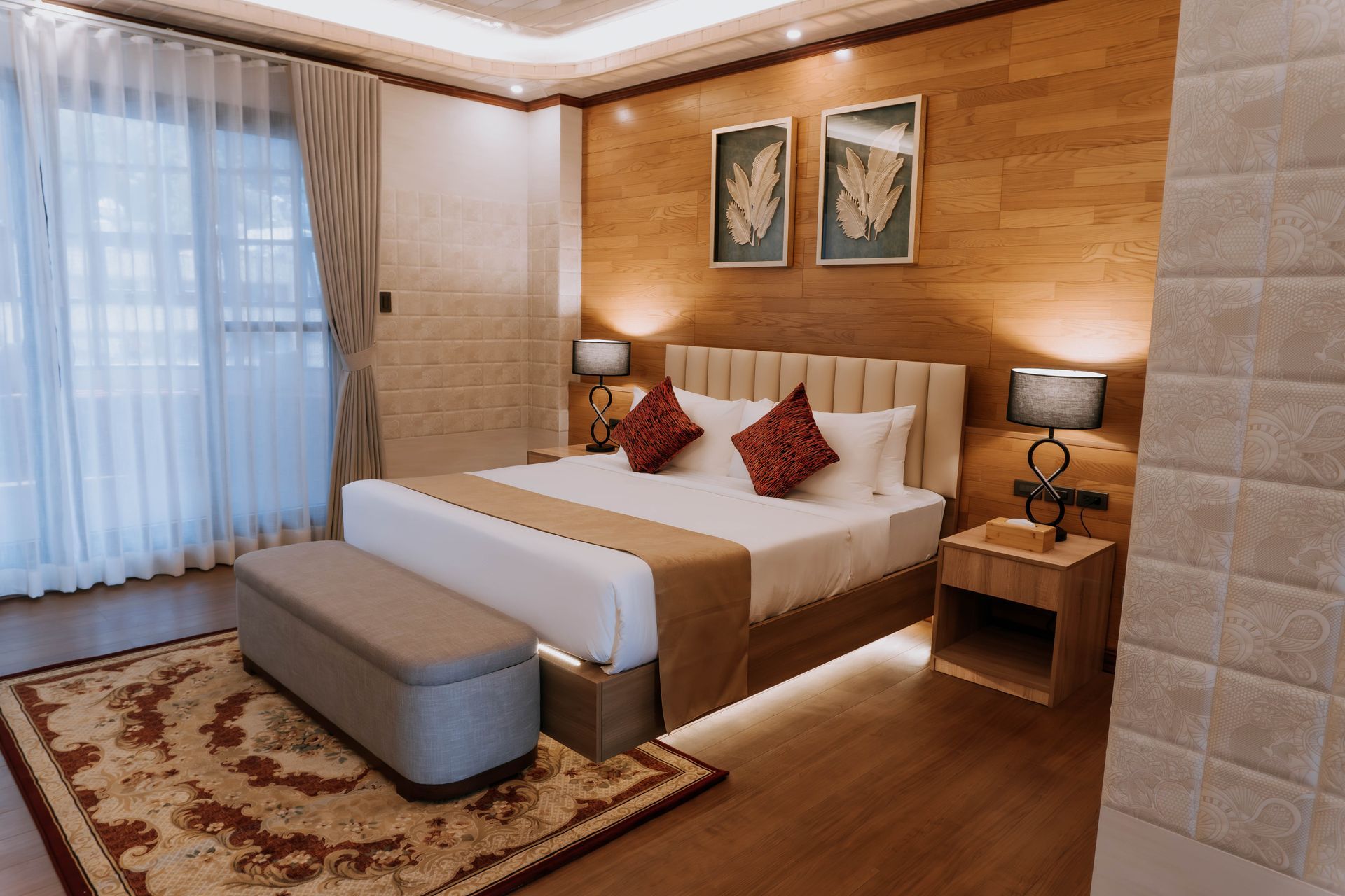 Bedroom with bed, nightstands, lamps, artwork, and wood paneling on the wall.