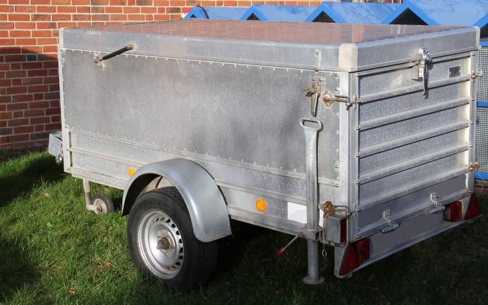 A Silver Trailer is Parked in the Grass in Front of a Brick Building — Boyd's Fabrications In Gordonvale, QLD