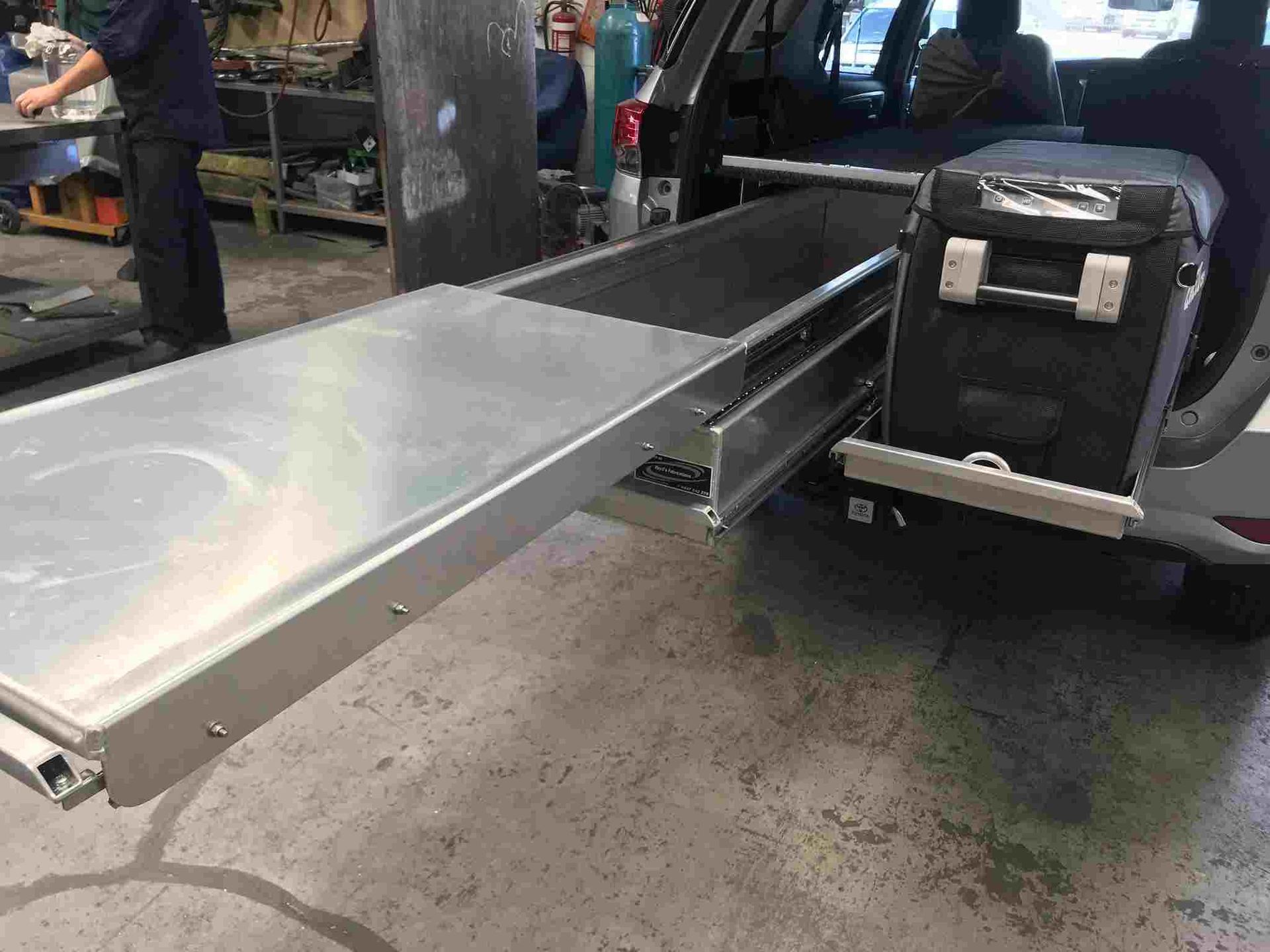 A Man is Standing Next to a Car With a Tray in the Back — Boyd's Fabrications In Portsmith, QLD 