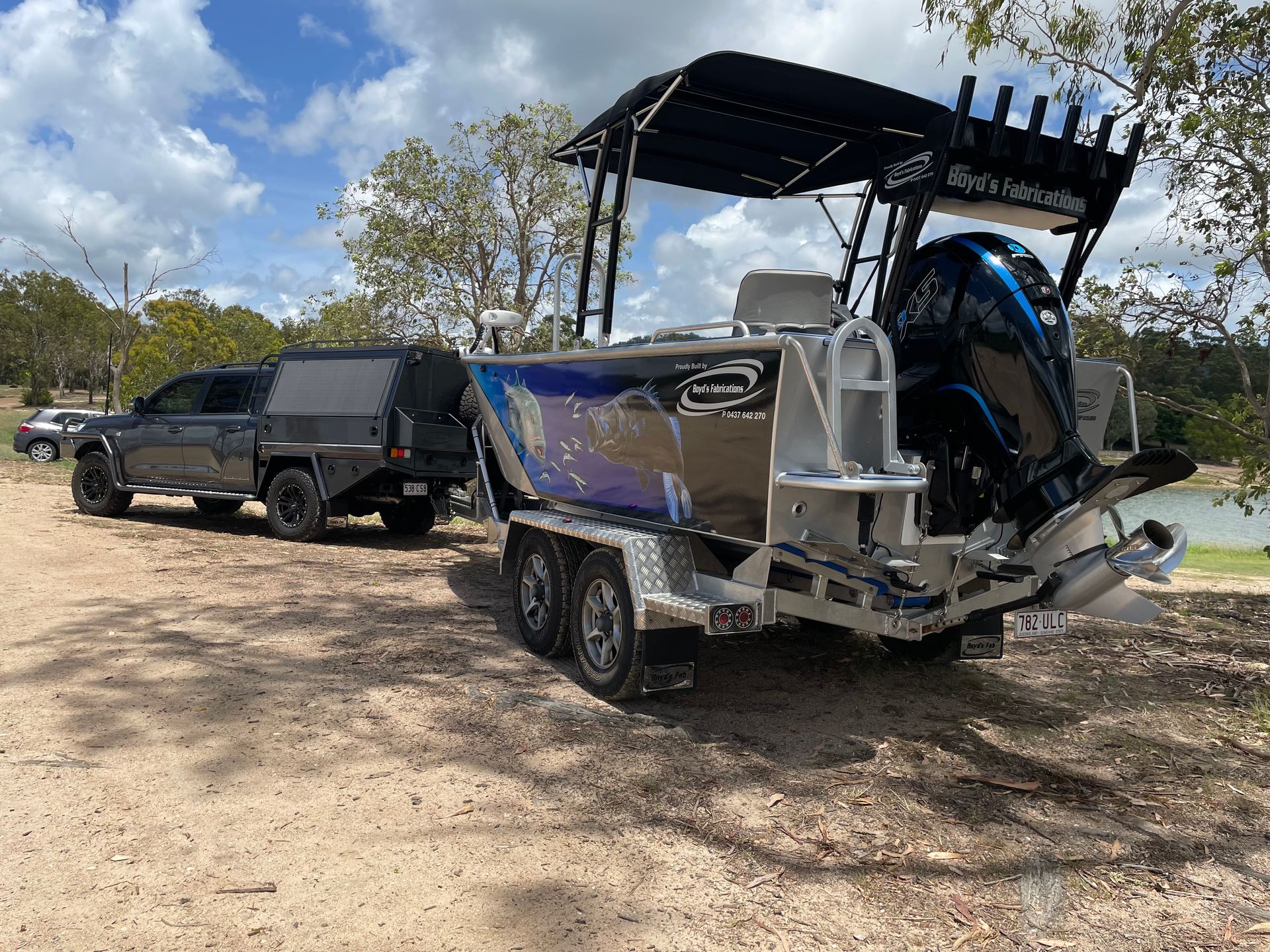 Black truck towing a silver boat on a trailer near a body of water, under a partly cloudy sky.— Boyd's Fabrications In Portsmith, QLD 