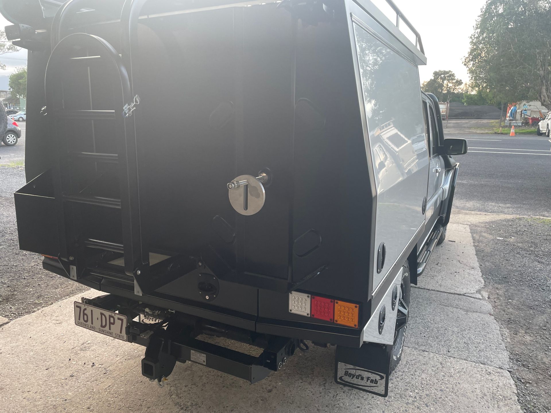 Black work truck with a canopy and ladder, parked outdoors on a sidewalk.— Boyd's Fabrications In Portsmith, QLD 