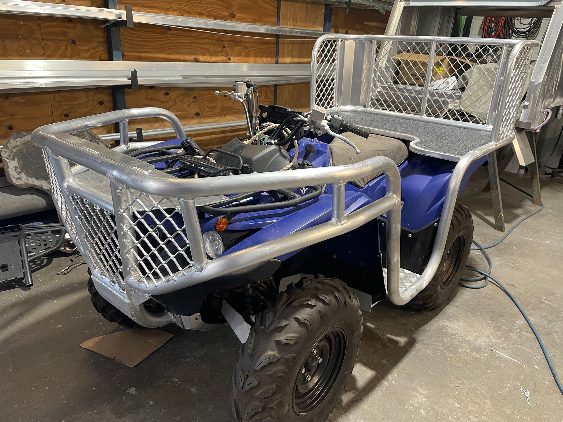 Blue ATV with custom metal front and rear cargo racks in a workshop. — Boyd's Fabrications In Portsmith, QLD