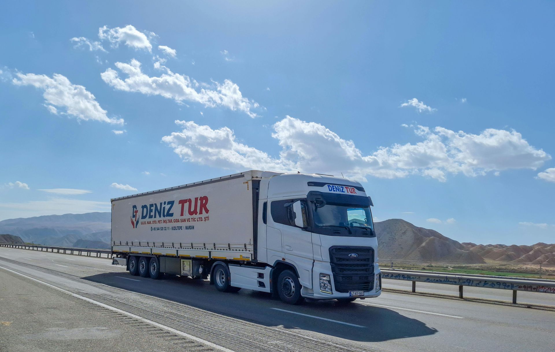 A white semi truck is driving down a highway.