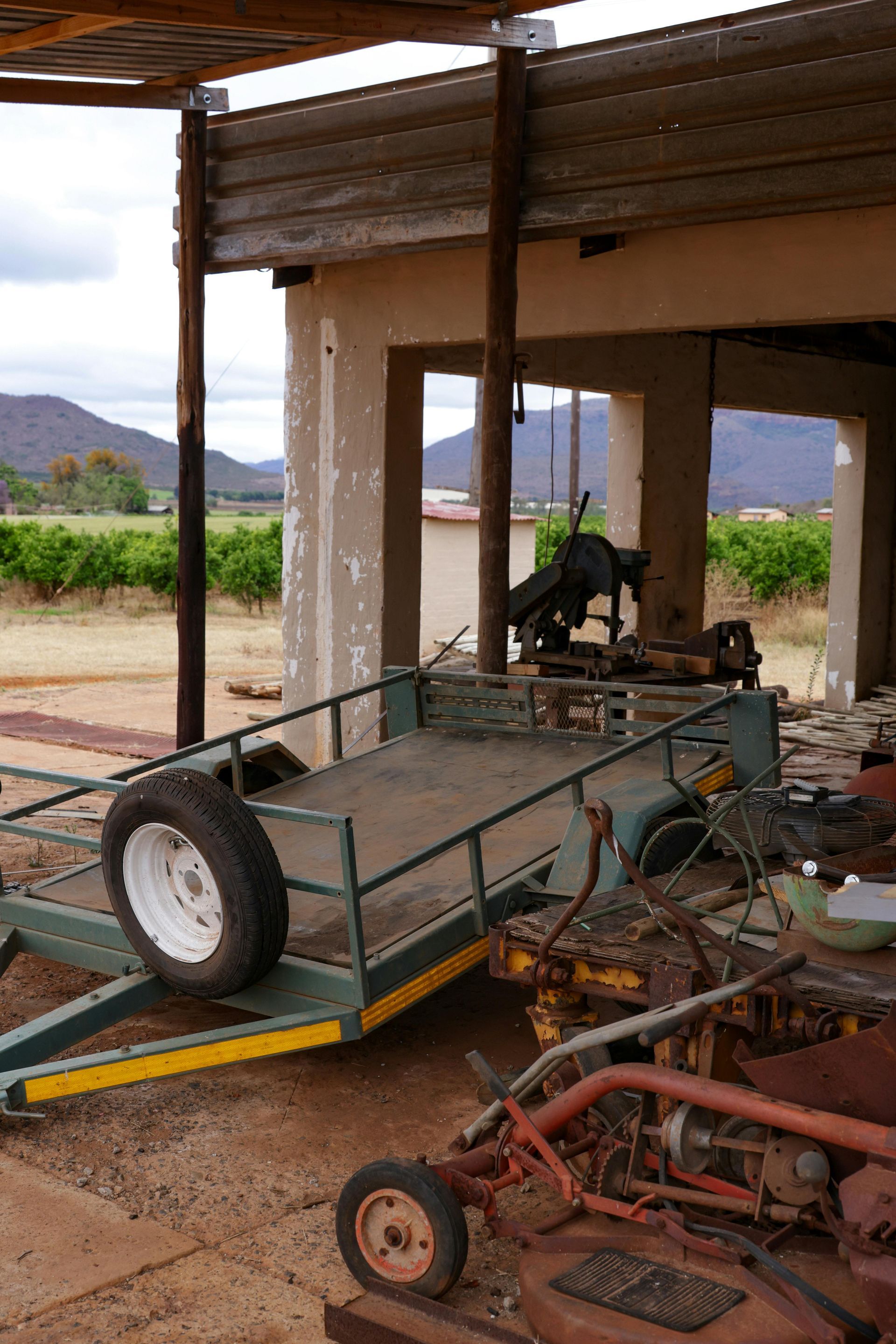Partially built off-road cart frame in a rustic shed, with tires and tools scattered nearby.