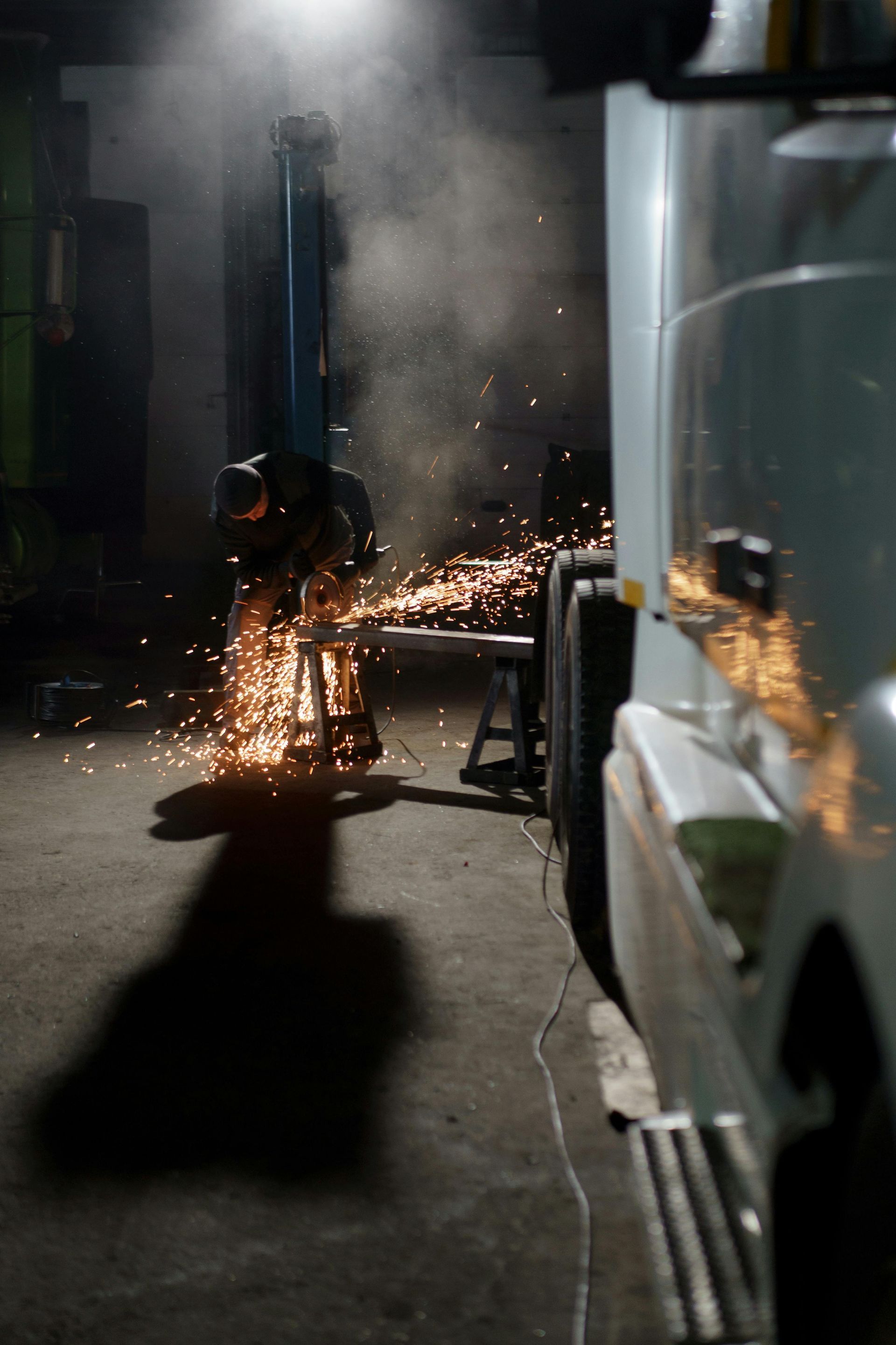 Worker cutting metal with sparks flying in a dark industrial alley