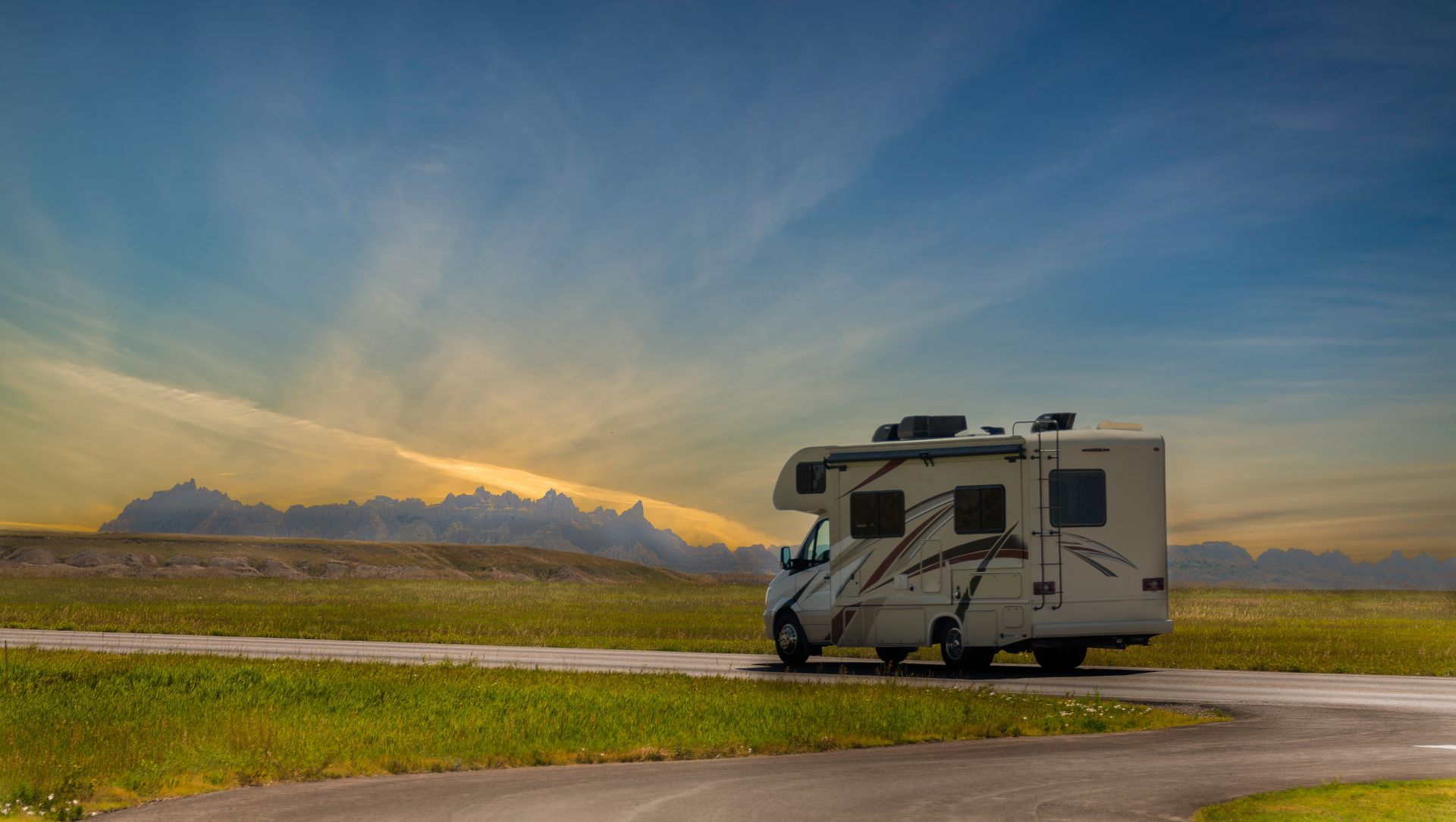 A rv is parked on the side of a road in the middle of a field.