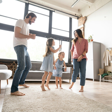 Family standing together in a bright living room, with two children between two adults