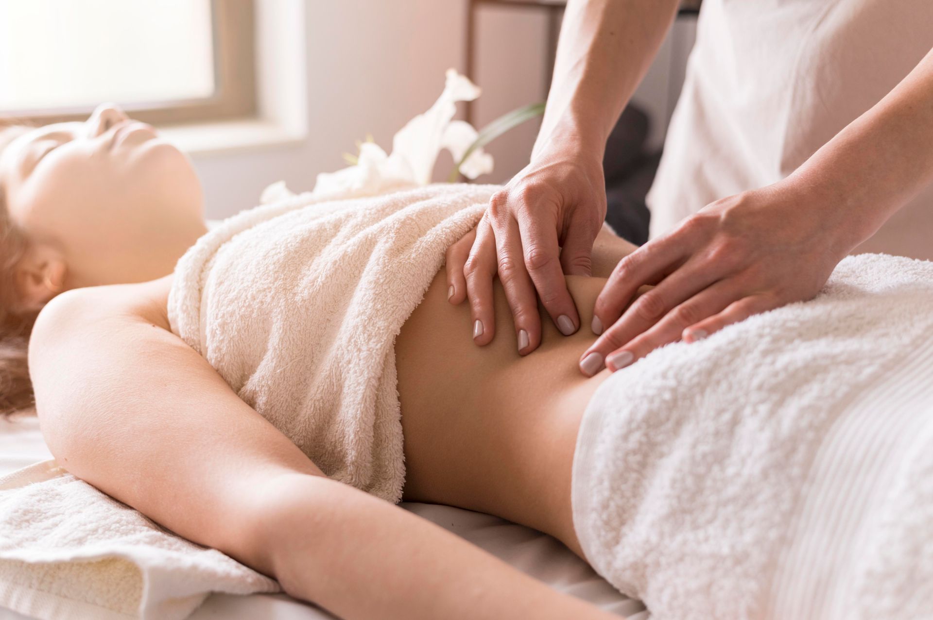 Una mujer envuelta en una toalla está recibiendo un masaje en un spa.