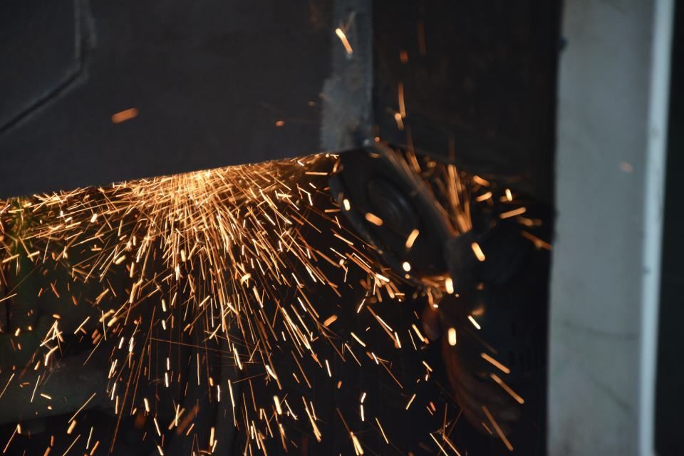 person is grinding a piece of metal with sparks coming out of it.