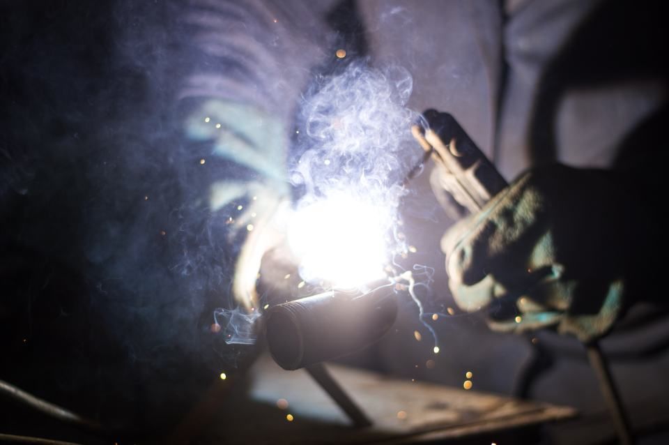 A person is welding a piece of metal in a dark room.