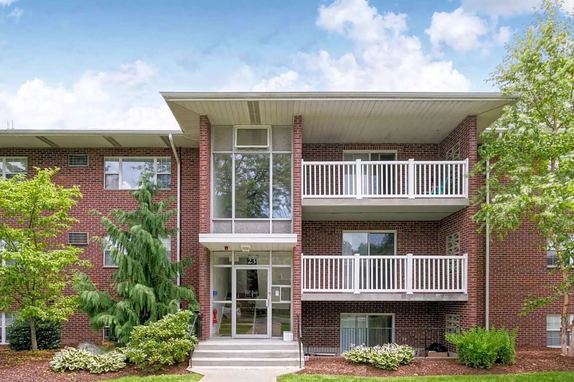 Front exterior of brick apartment building with balconies at Waltham Overlook Apartments in Waltham, MA.