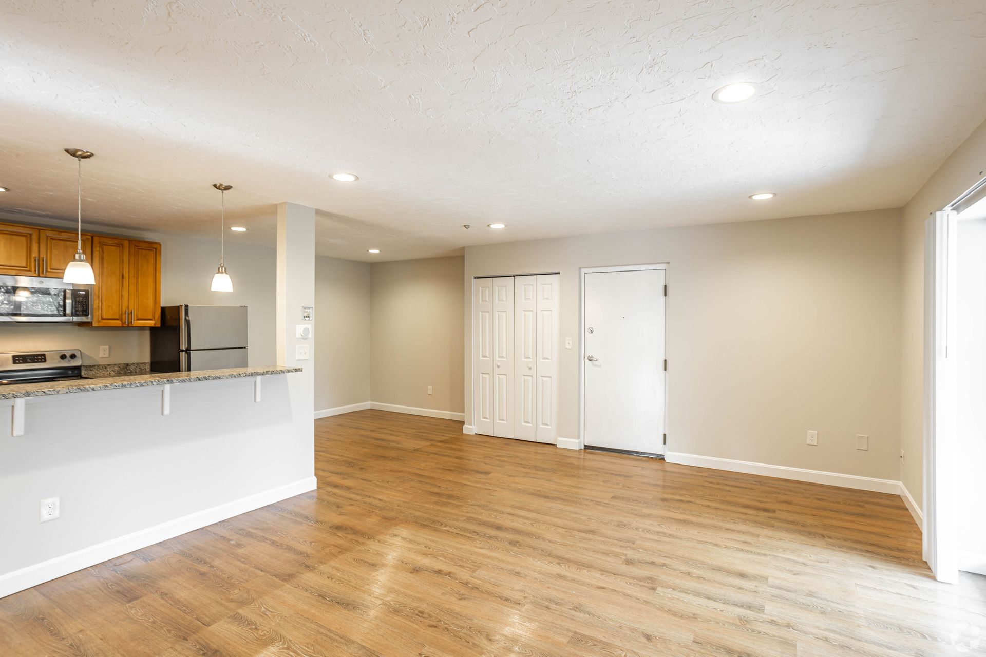Open living area with kitchen breakfast bar and wood-style flooring at Waltham Overlook Apartments in Waltham, MA.